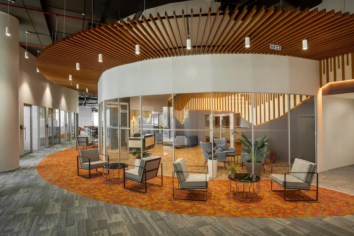 A corporate office interior with a circular glass meeting room and timber ceiling